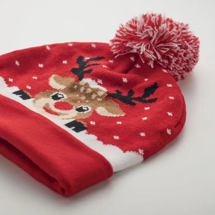 Bonita tricotata de craciun beanie rosu tricotat cu ren zambitor cu coarne negre si nas rosu decorat cu fulgi de nea albi