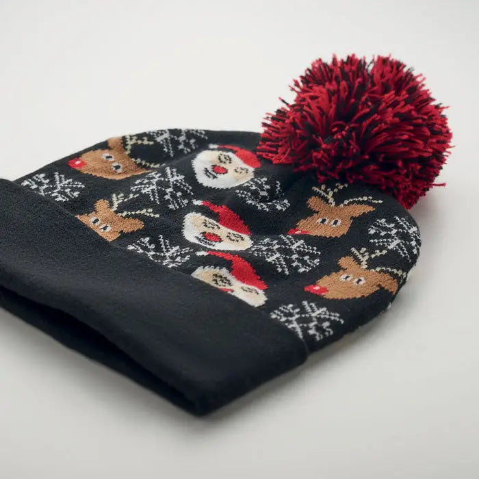 Bonita tricotata de craciun este o caciula neagra din lana cu modele festive de ren, mos craciun, fulgi de zapada si ciucure rosu