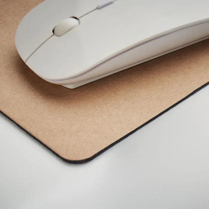 Un mouse wireless alb elegant pe un covoras pentru mouse din hartie reciclata de culoare pluta cu margini cusute negre