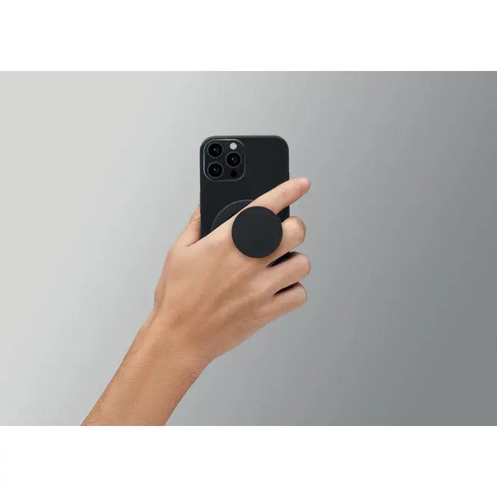 Suport magnetic negru circular din plastic atașat pe spatele unui smartphone pentru utilizare confortabilă