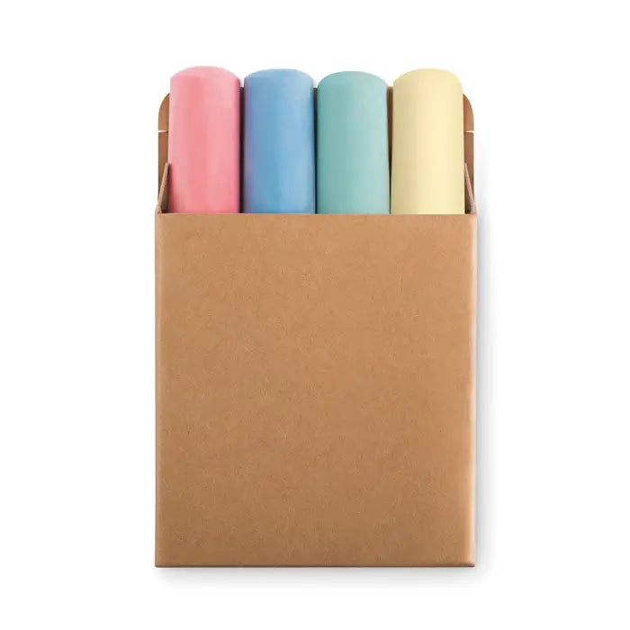 Un set de patru betisoare de creta pastelate in roz albastru verde si galben aranjate intr-o cutie de carton maro simpla