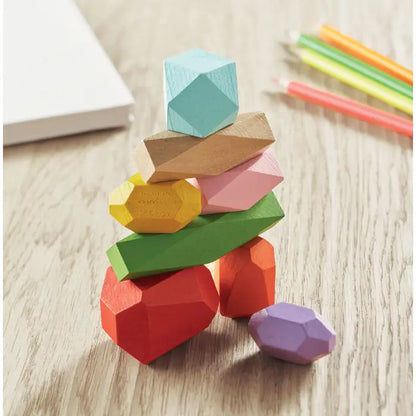 O stivă de opt pietre de lemn colorate geometrice cu un cub albastru deschis în partea de sus în punga transparentă