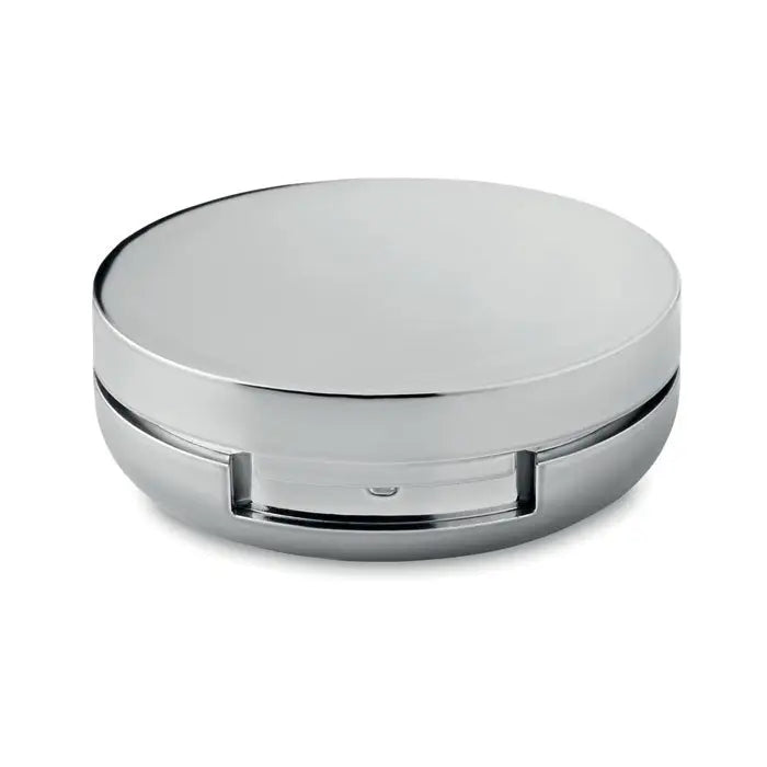 Un balsam de buze prezentat într-o oglindă compactă rotundă, cu finisaj cromat lucios și design minimalist