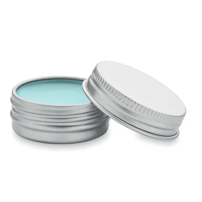 Balsam de buze vegan într-o cutie rotundă din argint cu un balsam de culoare albastru deschis în interior