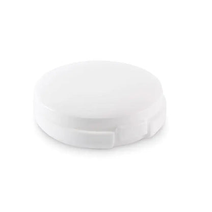 Balsam de buze vegan într-o cutie compactă din plastic alb cu capac rotunjit și margini ușor zimțate