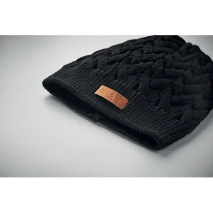 Bonita din tricot cablu rpET este o caciula neagra cu snur texturat si patch maro din piele pe margine pliata