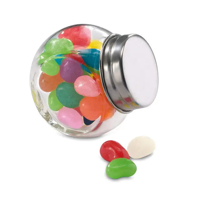 Borcan de sticla cu jeleu colorat in borcan transparent cu capac metalic argintiu si jeleuri risipite in fata