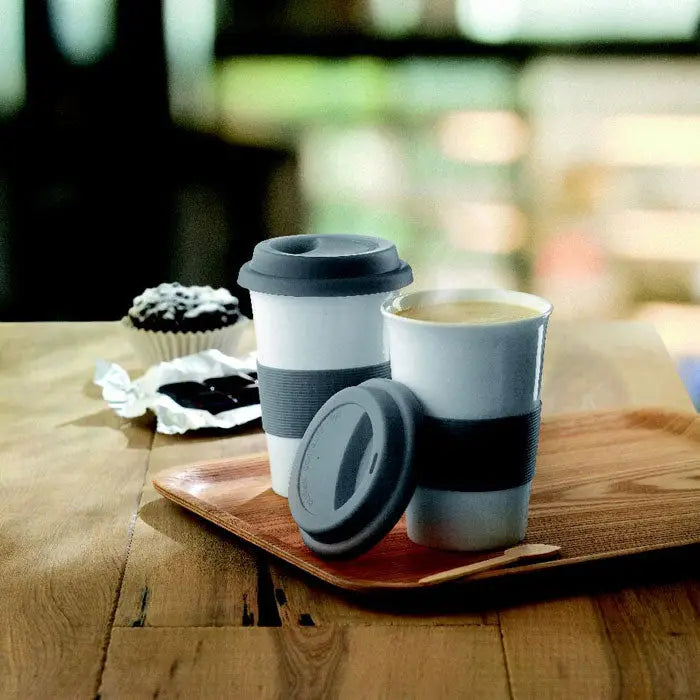 Cana din ceramica alba cu capac si manson gri din silicon, una deschisa cu bautura fierbinte aburinda