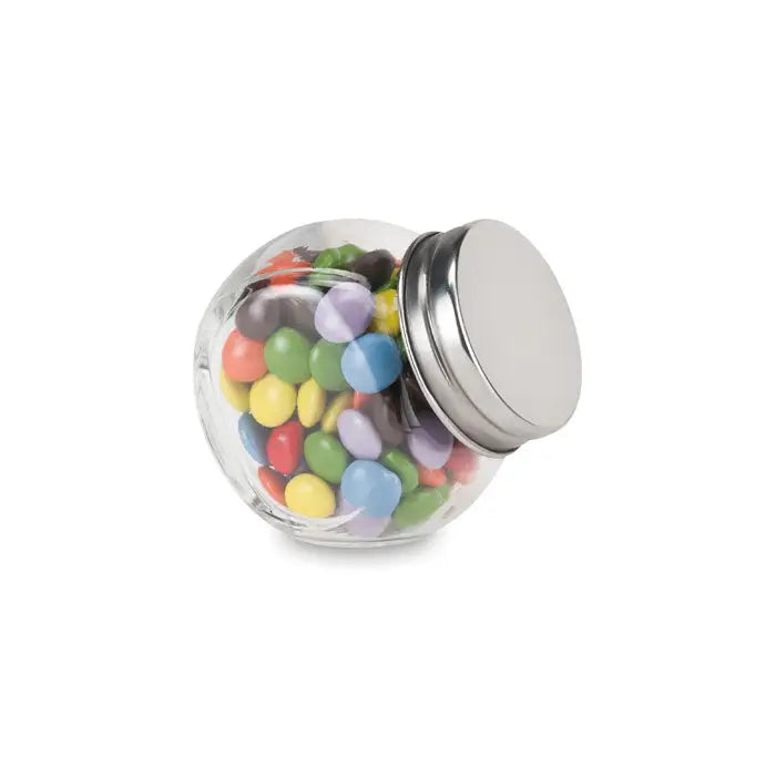 Borcan de sticlă transparent cu capac metalic argintiu umplut cu bomboane colorate ciocolata in suport de sticla