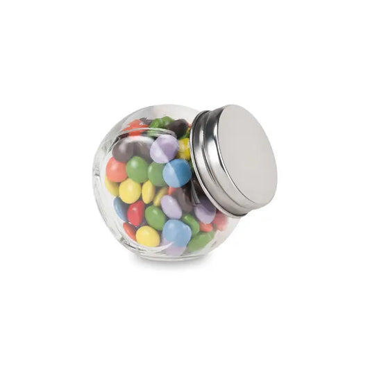Borcan de sticlă transparent cu capac metalic argintiu umplut cu bomboane colorate ciocolata in suport de sticla