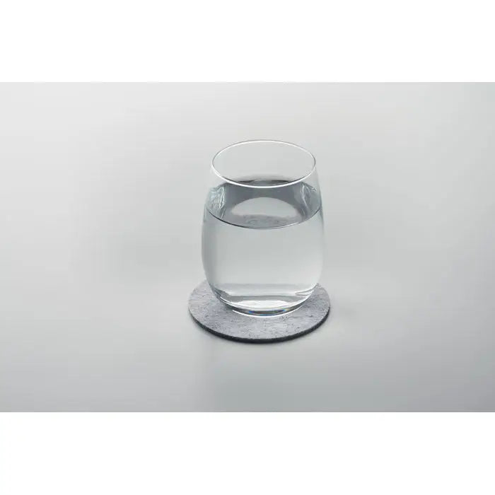 Coaster rotund din fetru rpet gri cu pahar de sticla transparent umplut cu apa pe el