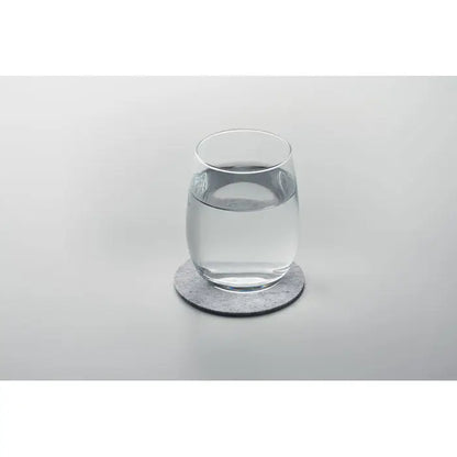 Coaster rotund din fetru rpet gri cu pahar de sticla transparent umplut cu apa pe el
