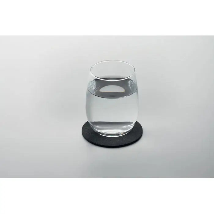 Coaster rotund din fetru rpet negru cu pahar transparent umplut cu apă așezat deasupra