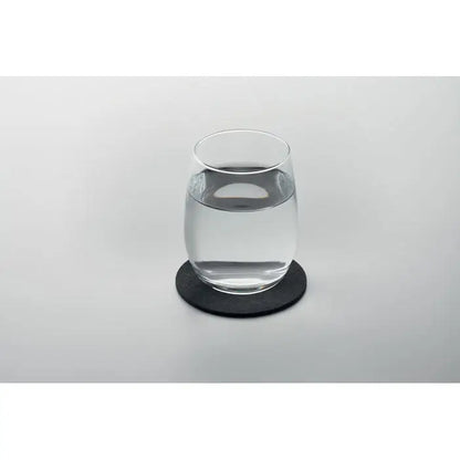 Coaster rotund din fetru rpet negru cu pahar transparent umplut cu apă așezat deasupra