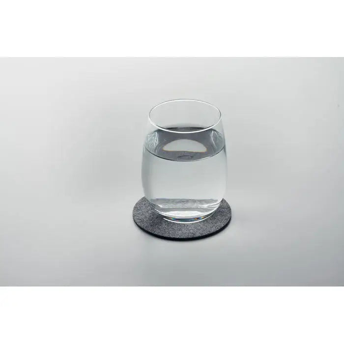 Coaster rotund din fetru rpet gri texturat cu pahar transparent cu apă așezat deasupra