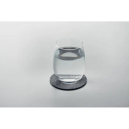 Coaster rotund din fetru rpet gri texturat cu pahar transparent cu apă așezat deasupra