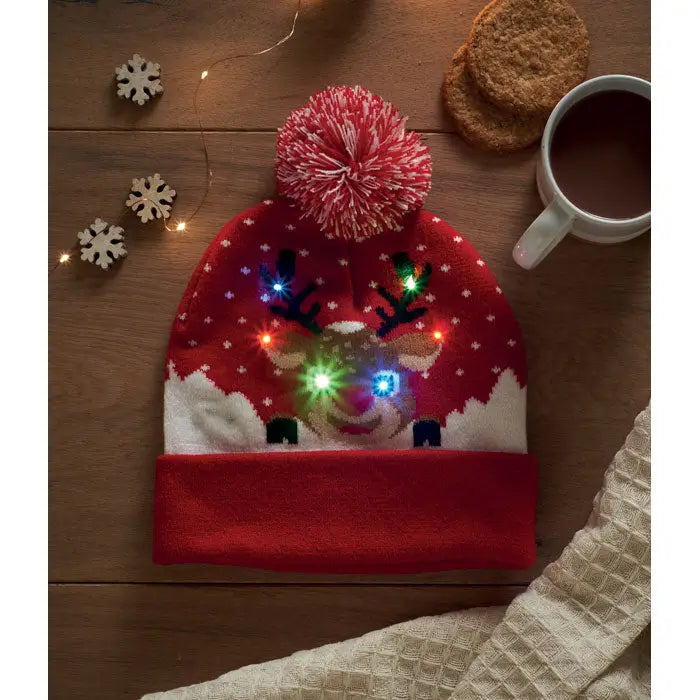 Beanie tricotat craciun rosu cu ren luminat led ochi si coarne si model fulgi de nea plus ciucure roz pufoasă