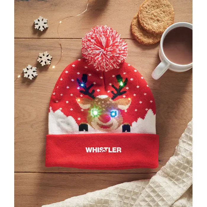 Beanie roșu tricotat crăciun cu față de ren iluminată led și model alb cu fulgi de nea și ciucure roșu-alb