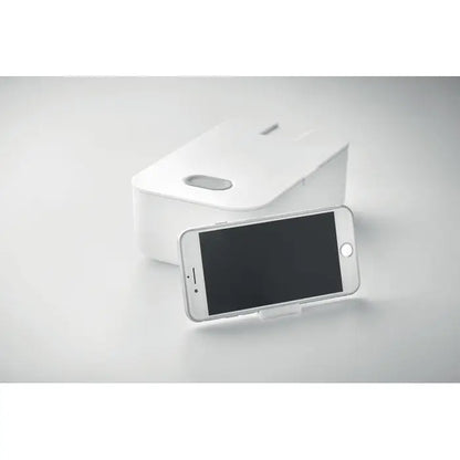 Stand telefon alb dreptunghiular din pp cu mâner decupat și suprafață netedă în spatele unui smartphone argintiu cutie de pranz din pp