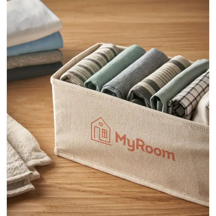 Cutie mare de depozitare bej din pânză 220 gr/m² cu logo portocaliu myroom, umplută cu prosoape pliate