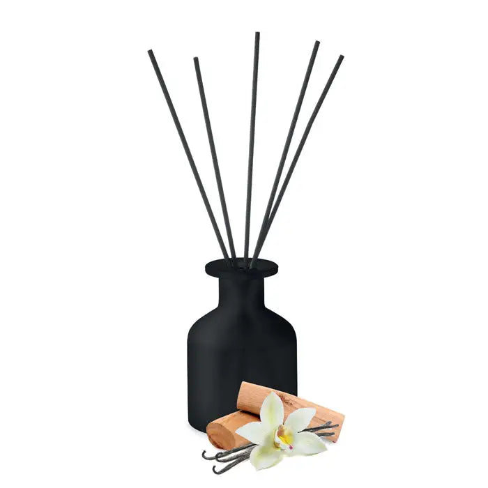 Difuzor de trestie de parfum de casa din sticla mata neagra cu bete subtiri negre si pastai de vanilie langa el