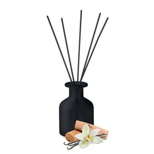 Difuzor de trestie de parfum de casa din sticla mata neagra cu bete subtiri negre si pastai de vanilie langa el