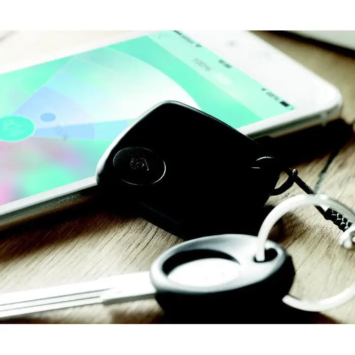 Dispozitiv anti-pierdere negru din silicon cu logo circular atasat la chei prin snur negru