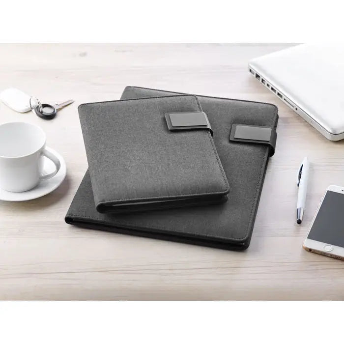 Dosar a4 cu power bank două dosare din material texturat gri închis cu curele din piele ecologică pe birou din lemn