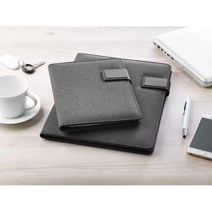 Dosar a4 cu power bank două dosare din material texturat gri închis cu curele din piele ecologică pe birou din lemn