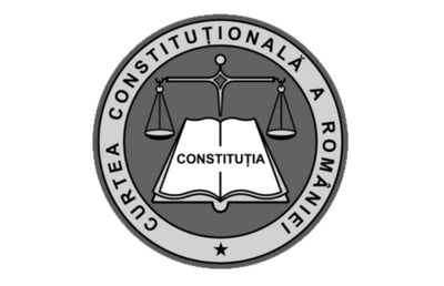 Emblemă circulară gri cu o balanță echilibrată deasupra unei cărți deschise cu cuvântul 'constituția' înscris, înconjurată de textul 'curtea constituțională a româniei'.