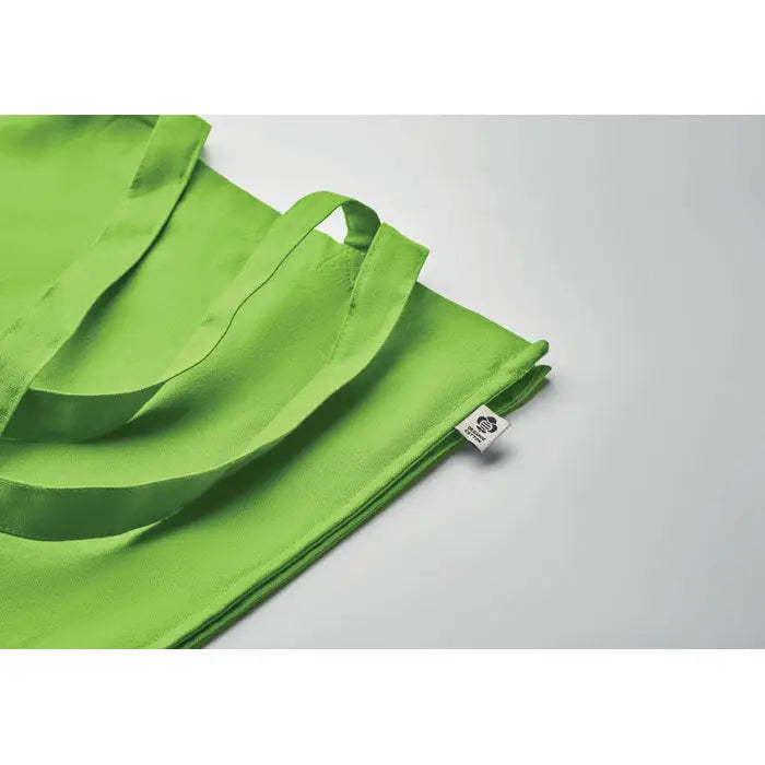 Geanta de cumparaturi din bumbac organic cu manere rezistente si eticheta alba pe fond verde lime