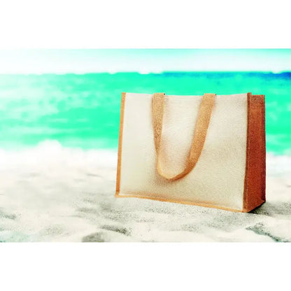 Beige și maro geantă de cumpărături din iută și pânză cu mâner robust pe plajă nisipoasă