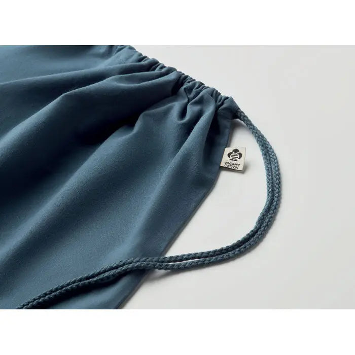 Geanta din bumbac organic teal cu cordon impletit si eticheta mica ce indica materialul organic