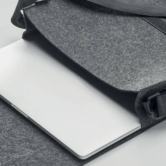 Geanta laptop din fetru rpet gri cu bretea neagra tinand un macbook argintiu snug