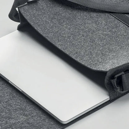 Geanta laptop din fetru rpet gri cu bretea neagra tinand un macbook argintiu snug