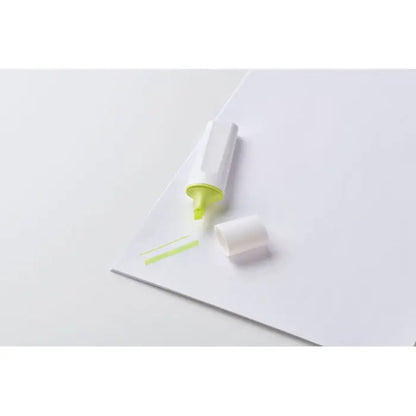 Un marker iluminator rpet alb cu varf si capac verde lime, pe hârtie albă, capac detașat lângă