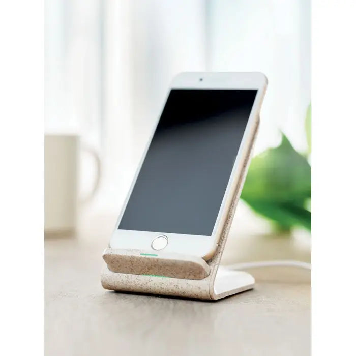 White iphone odihnindu-se pe un suport wireless de incarcare bej texturat din paie de grau incarcare 10w abs