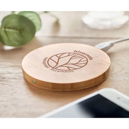 Un încărcător wireless circular din bambus 5w cu finisaj maro deschis și design gravat hivernale coworking stockholm