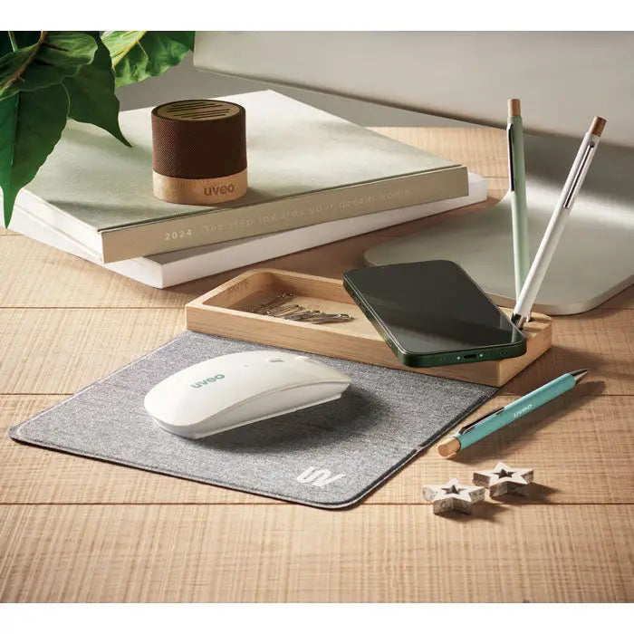 White wireless mouse pe mousepad texturat gri lângă încărcător wireless din bambus 15w