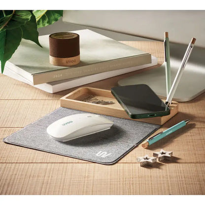 White wireless mouse pe mousepad texturat gri lângă încărcător wireless din bambus 15w