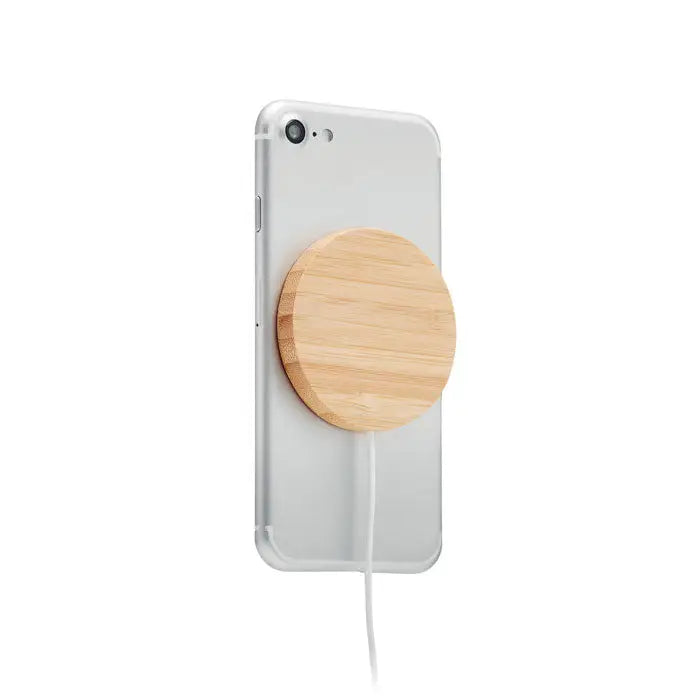 Incarcator wireless magnetic 10w circular din bambus maro deschis atasat pe spatele unui smartphone argintiu