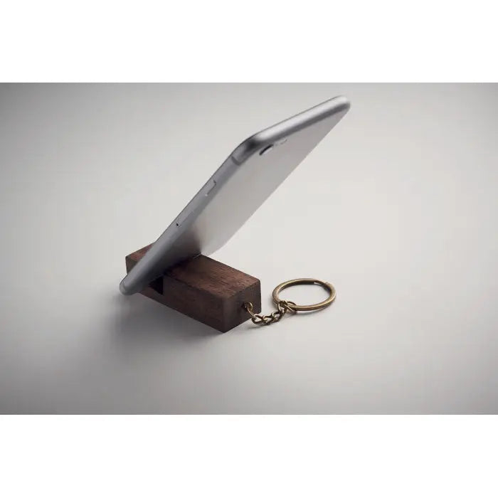 Inel de chei din lemn inchis cu suport pentru telefon si smartphone argintiu asezat pe el