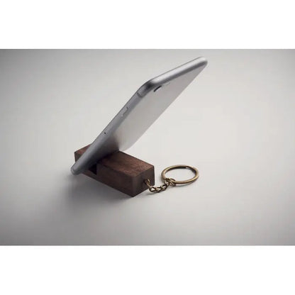 Inel de chei din lemn inchis cu suport pentru telefon si smartphone argintiu asezat pe el