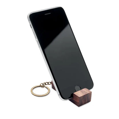 Inel de chei din lemn închis la culoare cu suport pentru telefon din alama ținând un iphone
