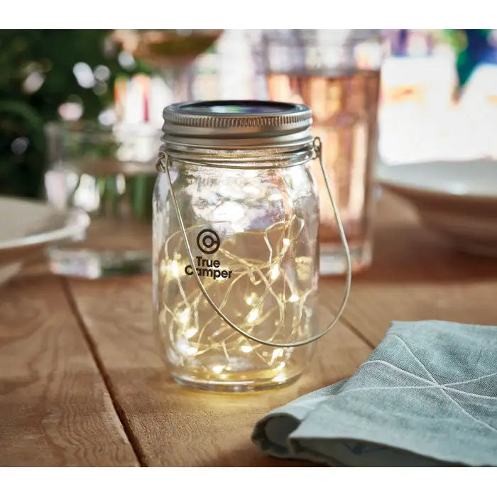 Lampa solara de exterior cu borcan zidar transparent si lumini led calde in capac metalic argintiu cu maner