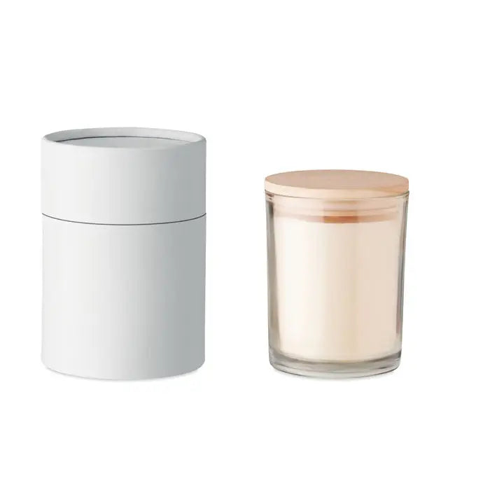Lumanare cu parfum de vanilie in borcan minimalist din sticla cu capac de lemn deschis si ceara alba cremoasa langa ambalaj cilindric alb