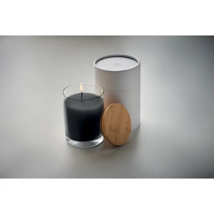 Lumanare cu parfum de vanilie în borcan transparent cu fitil aprins, ambalaj cilindric alb și capac din bambus