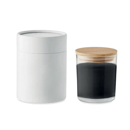 Lumanare cu parfum de vanilie in recipient cilindric alb langa borcan transparent cu capac de bambus si continut inchis