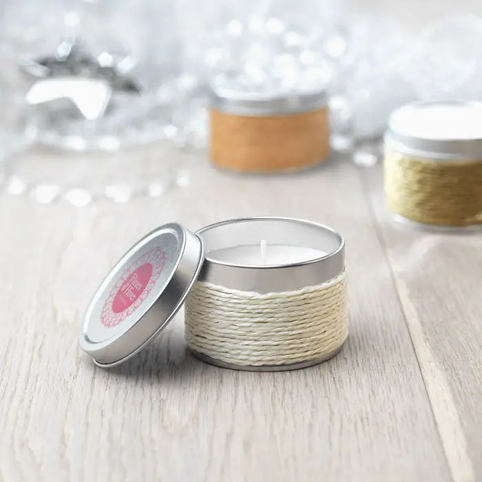 Lumanare cu parfum într-un recipient metalic crem înfășurat cu sfoară cu capac argintiu și etichetă roz decorativă