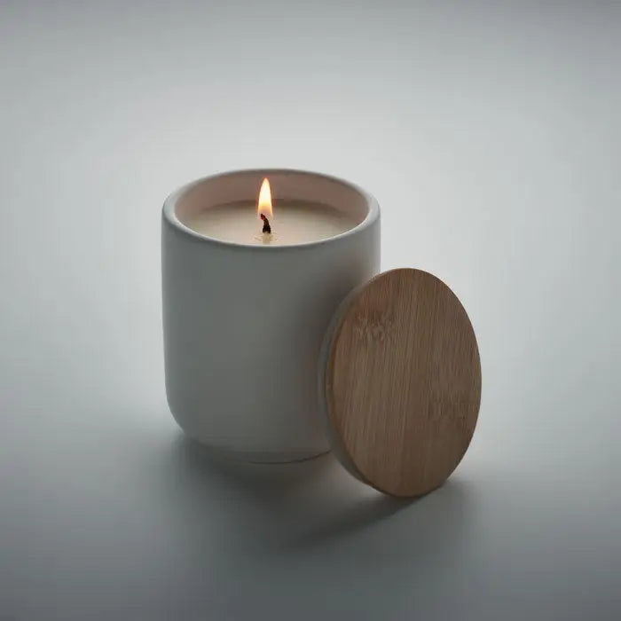 Lumanare de ceara pe baza de plante 200 gr in borcan ceramic alb cu fitil aprins si capac din bambus langa ea
